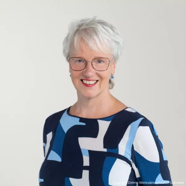 Frau Winkler mit silbernen Haaren, Brille, Lächeln und blau gemusterter Bluse (Copyright: Delme-Werkstätten/Marco Gallmeier)